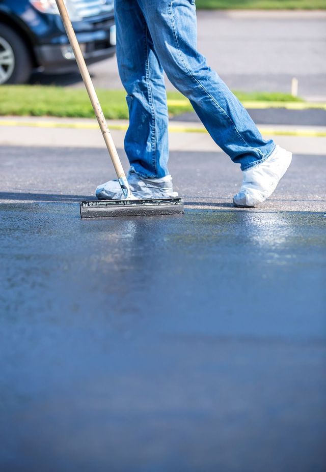 Two people’s legs in jeans and sneakers stepping on wet pavement near a street
