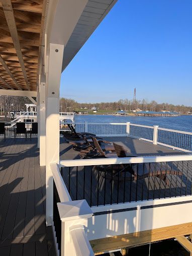 A deck with chairs and tables overlooking a body of water.