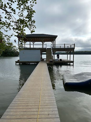 A wooden dock leading to a house on a lake.