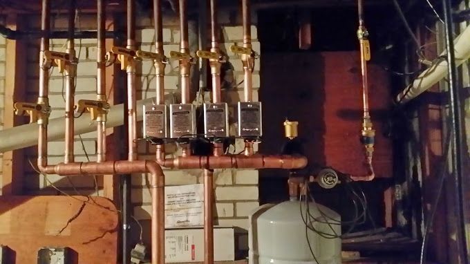 A brick wall with copper pipes hanging from it