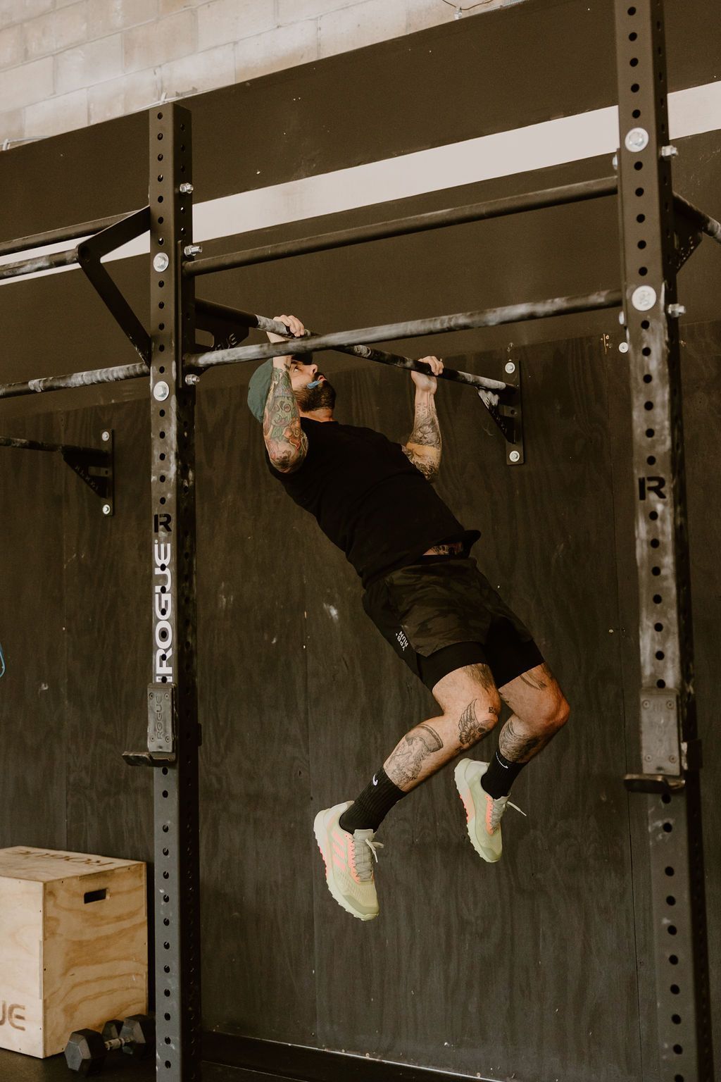 A man is doing a pull up on a bar in a gym.