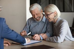 Two people review documents with an agent at a desk in an office