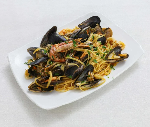 Piatto di spaghetti con cozze e gamberi in un sugo leggero, serviti su un piatto bianco.