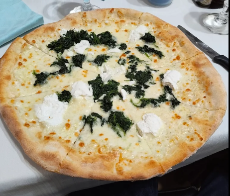 Pizza bianca con formaggio fuso ed erbe aromatiche verde scuro su un piatto