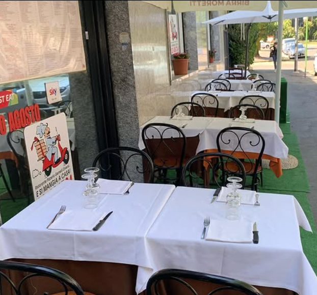 Tavolini da caffè all'aperto con tovaglie bianche e sedie disposti lungo un marciapiede