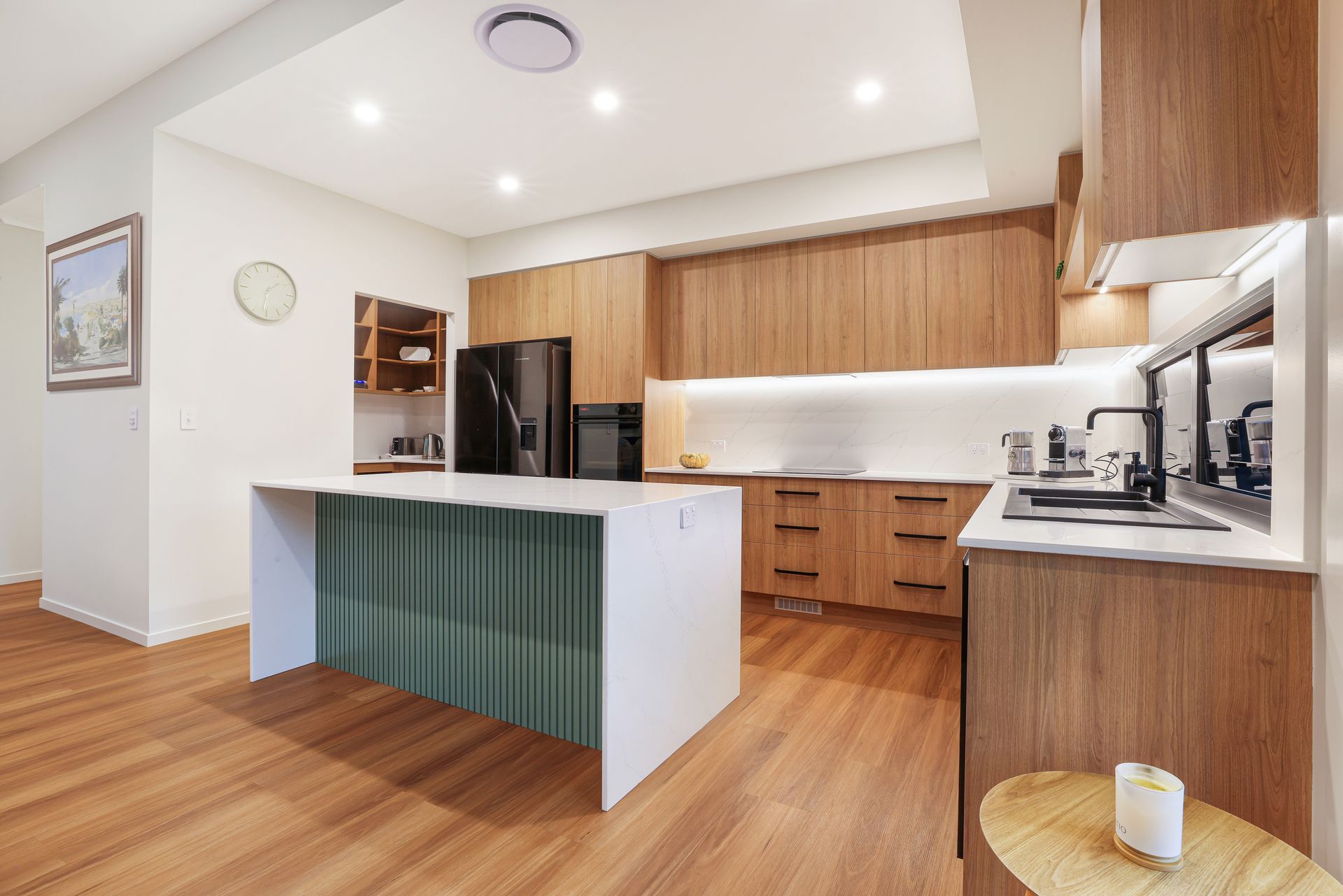 Modern open-plan kitchen and living area with white cabinetry, island, fireplace, and large windows.