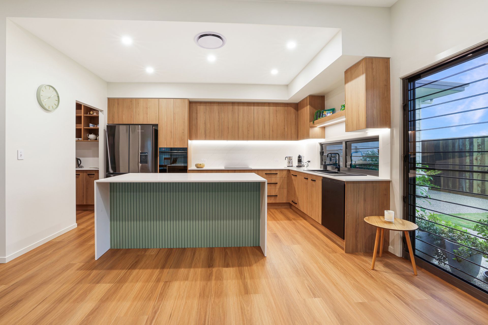 Modern Kitchen With Green Island and Large Windows Overlooking Greenery — Master Cabinets Bundaberg in Kensington, QLD