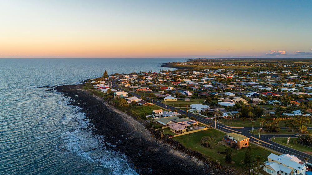 An Aerial View Of A City Next To The Ocean At Sunset — Master Cabinets Bundaberg in Bargara, QLD