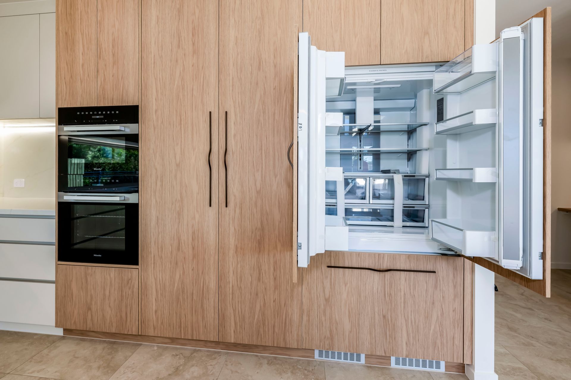 Modern kitchen with white island, wood accents, and glass wine room.