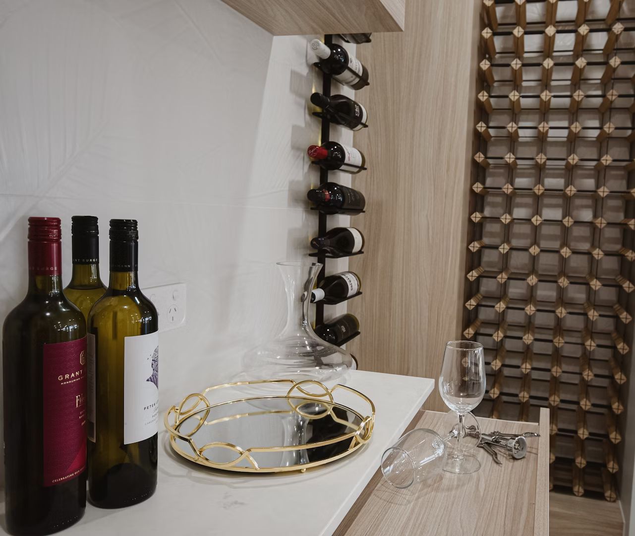 Wine bottles and glasses on a countertop with a wine rack.