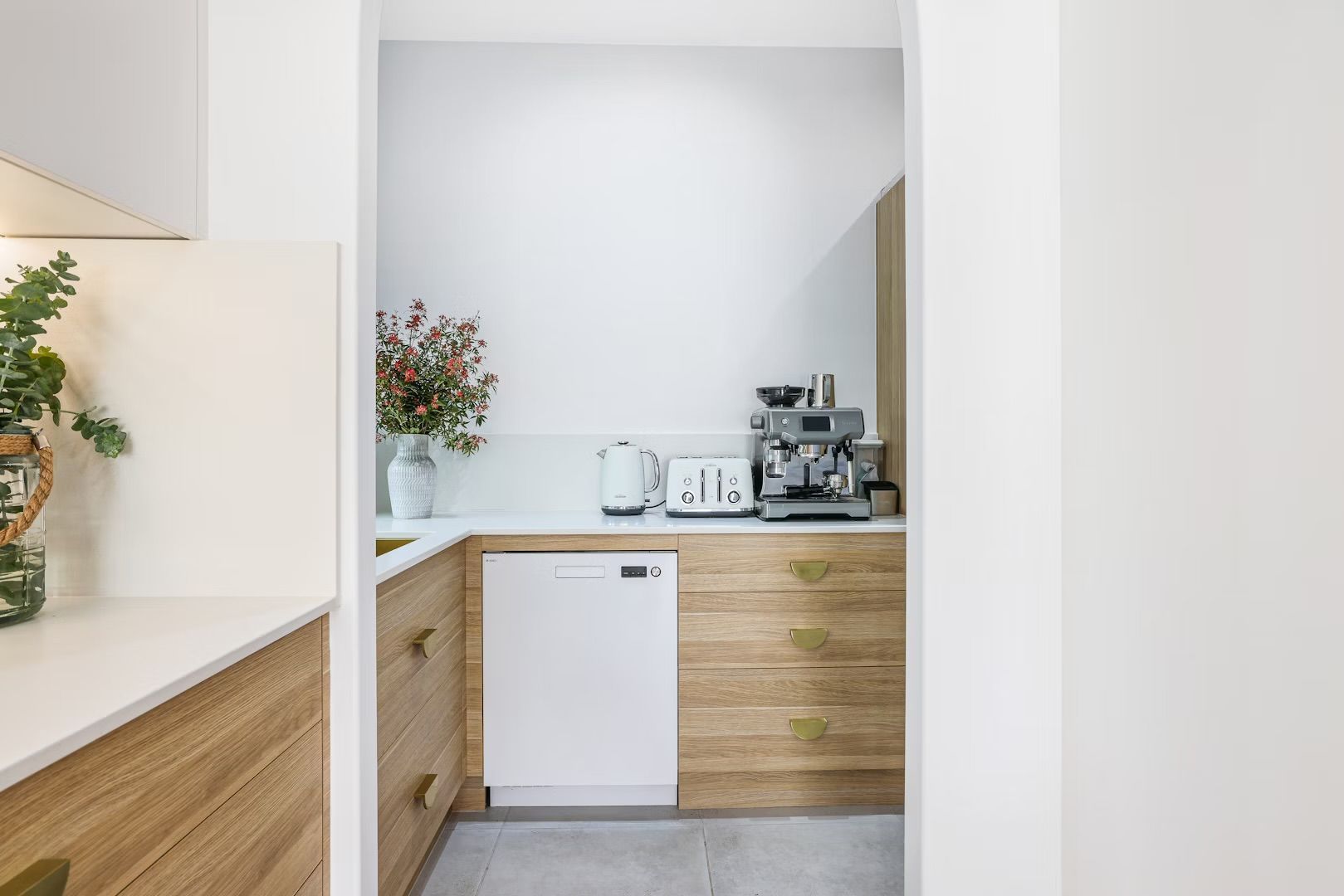Small kitchen nook with white walls, wood cabinets, and appliances like a coffee machine and toaster.