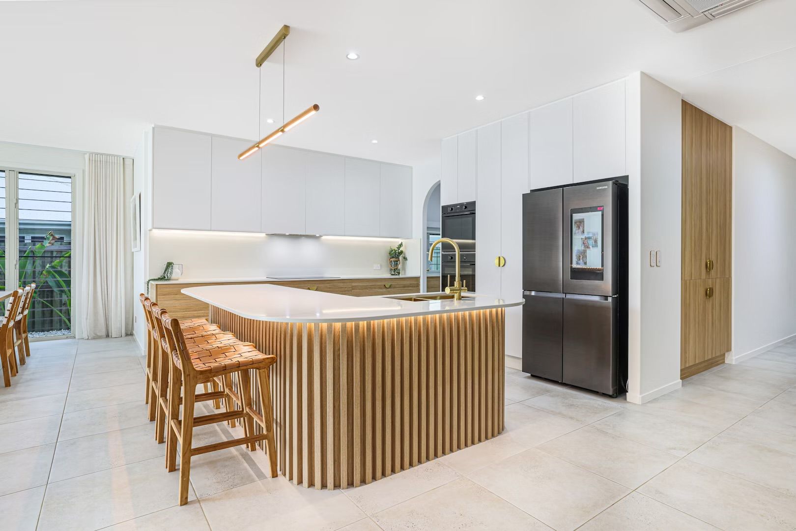 Modern kitchen with wooden island, white cabinets, and stainless steel refrigerator.