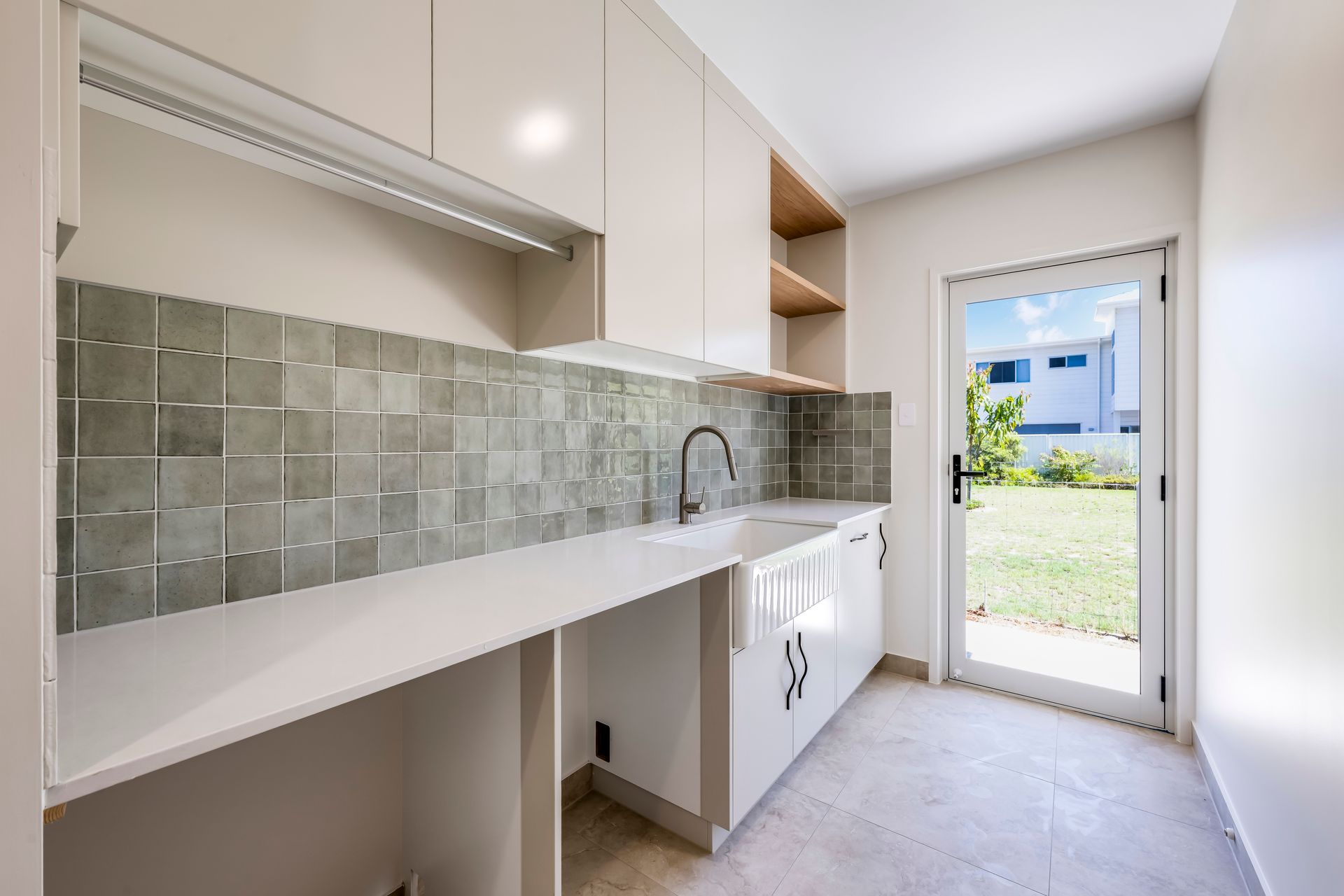 Laundry room with sink, and storage cabinets. Green feature tiles on white walls.