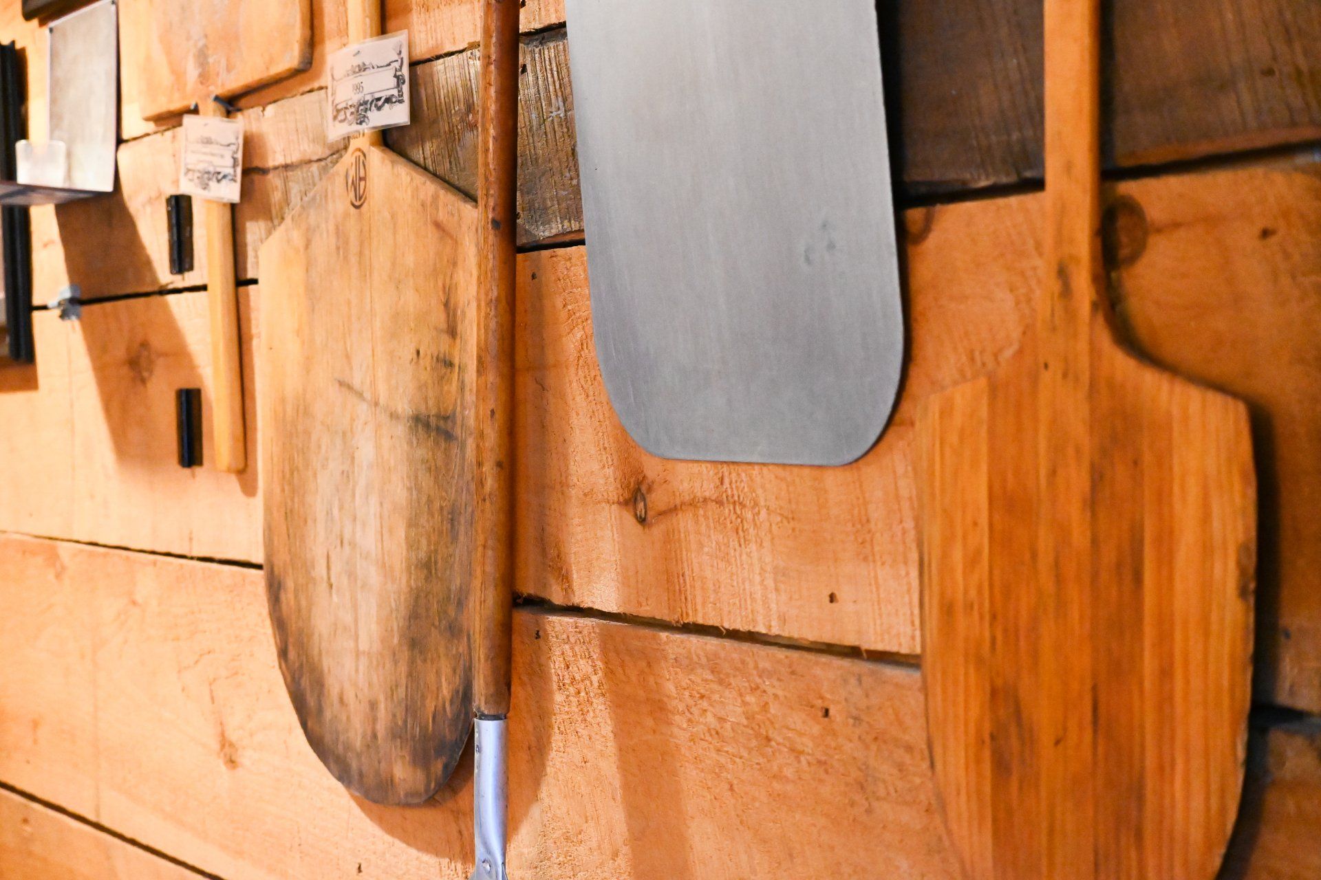 A wooden wall with a bunch of wooden cutting boards hanging on it.