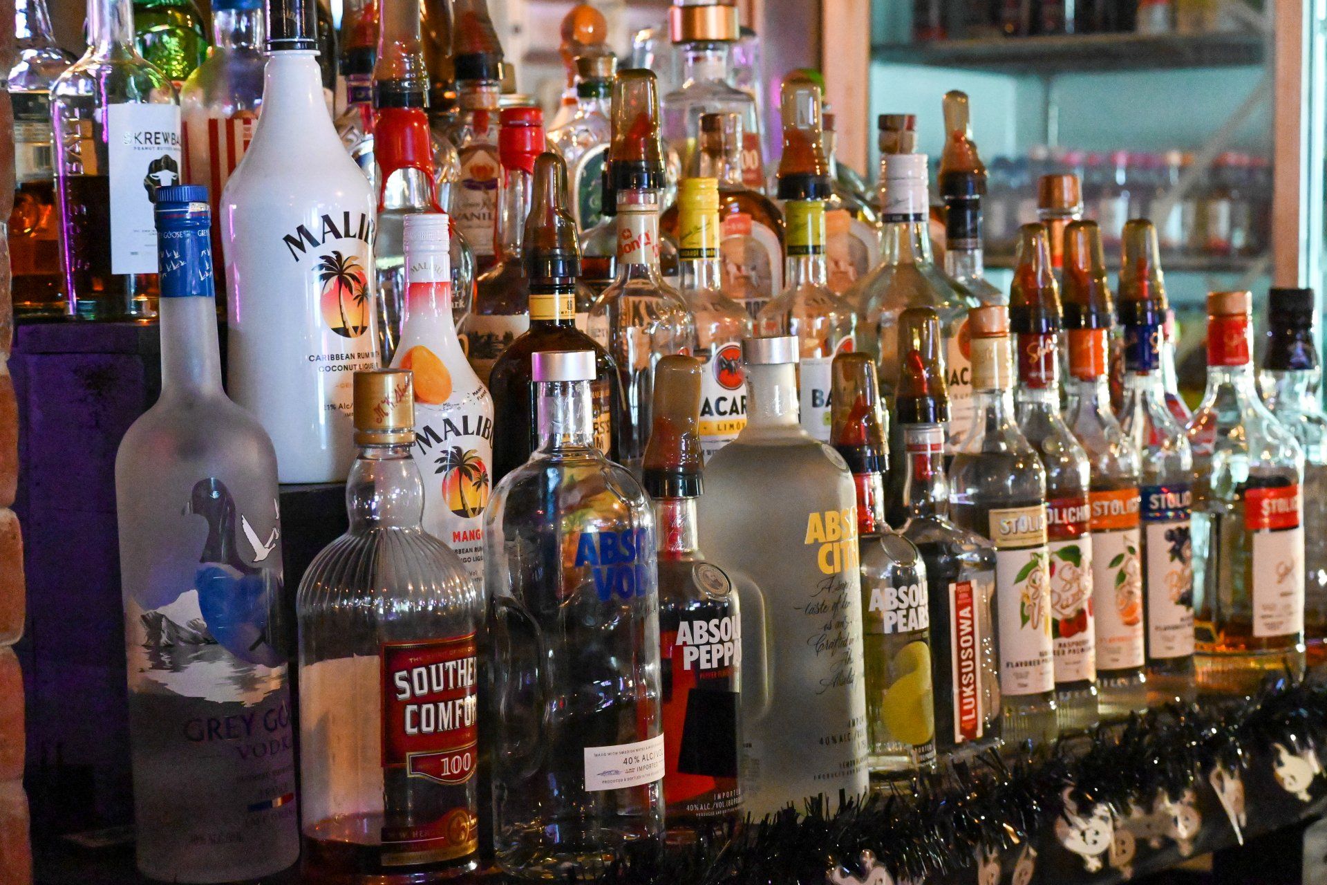 Many bottles of alcohol are lined up on a bar