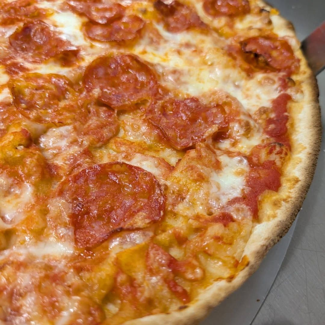 Primo piano della pizza al pepperoni con formaggio fuso e crosta croccante.