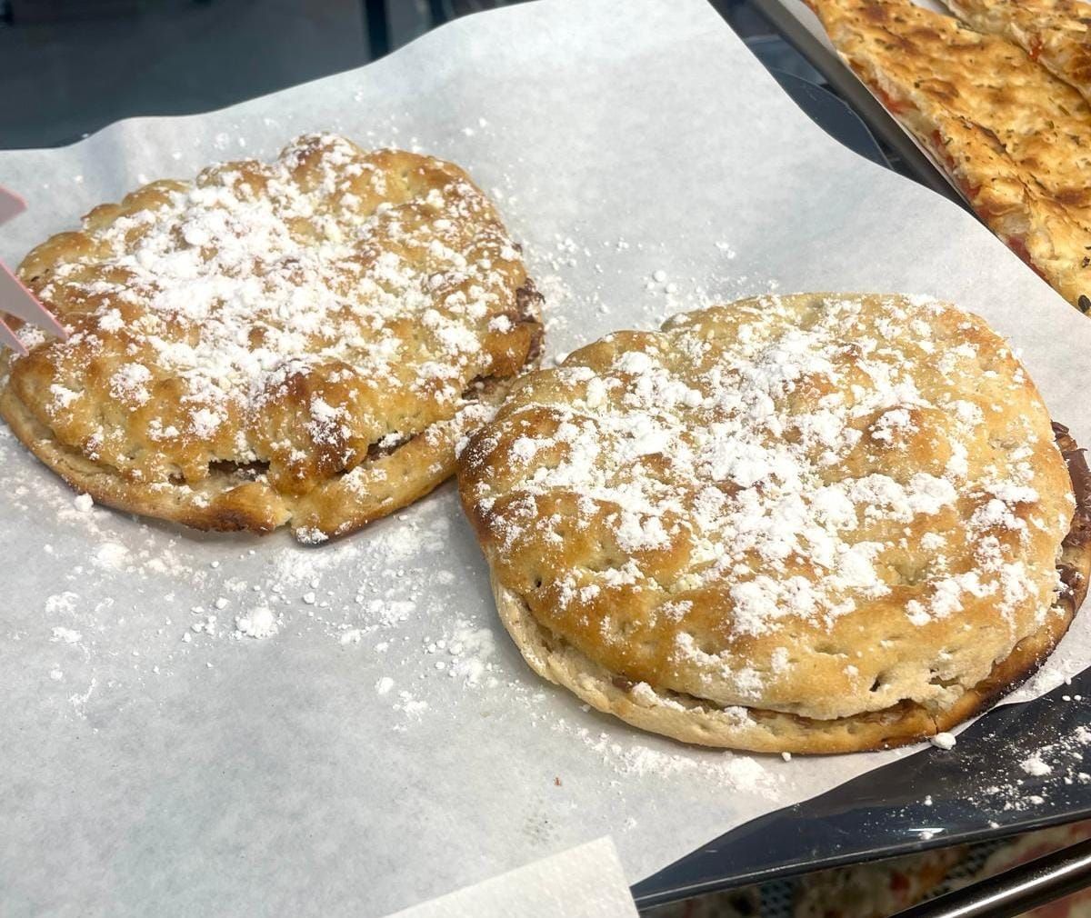 Due pasticcini rotondi spolverati con zucchero a velo su carta da forno.