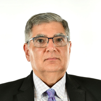 Studio headshot of a man in a suit and tie on a white background