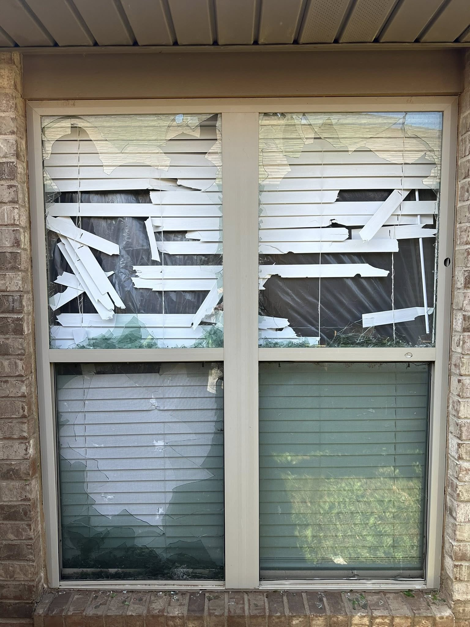 Two-pane window with damaged blinds and peeling paint. Lower sections show intact blinds. Building exterior.
