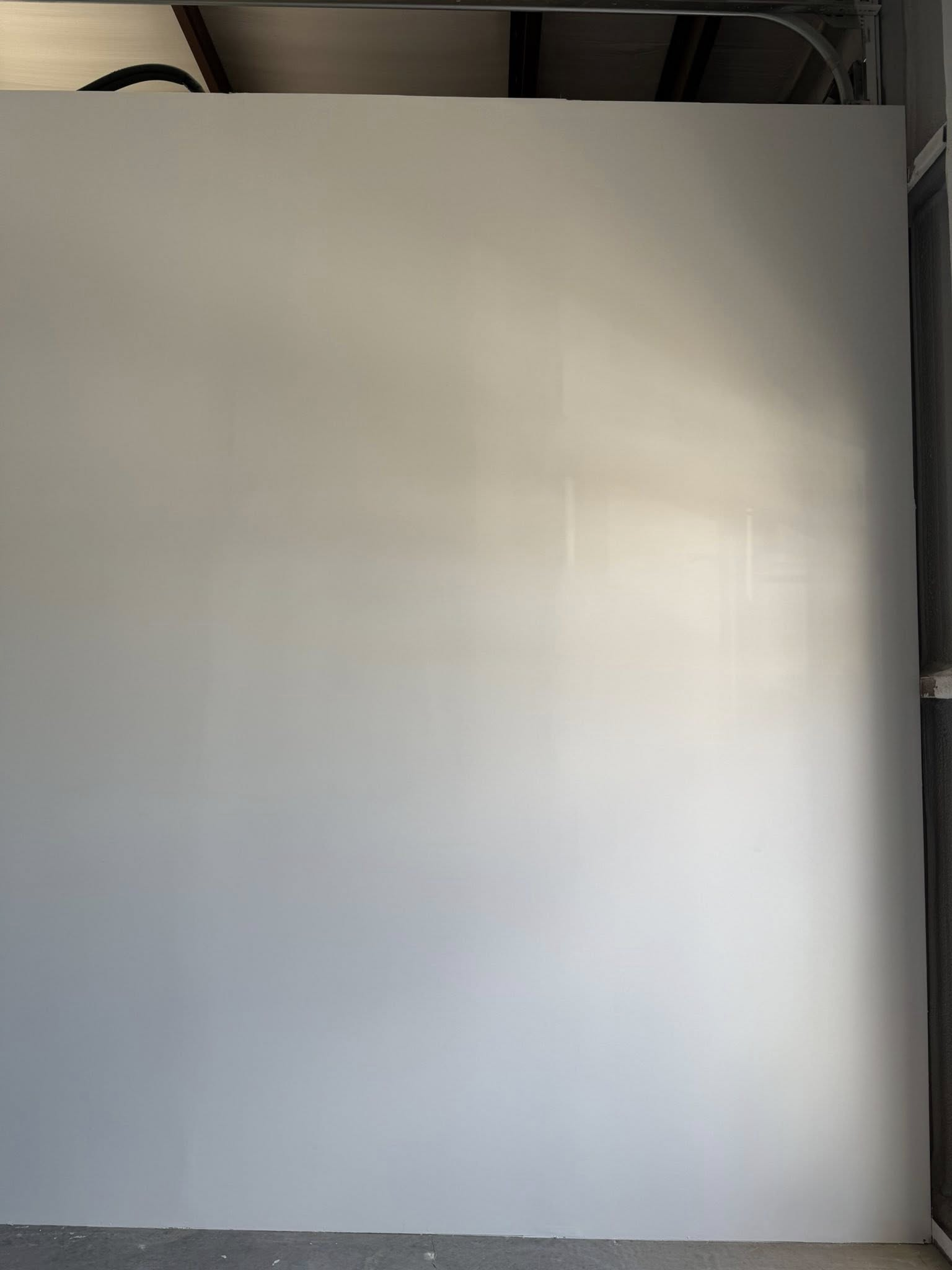 A blank, light gray wall with shadows, possibly under construction.