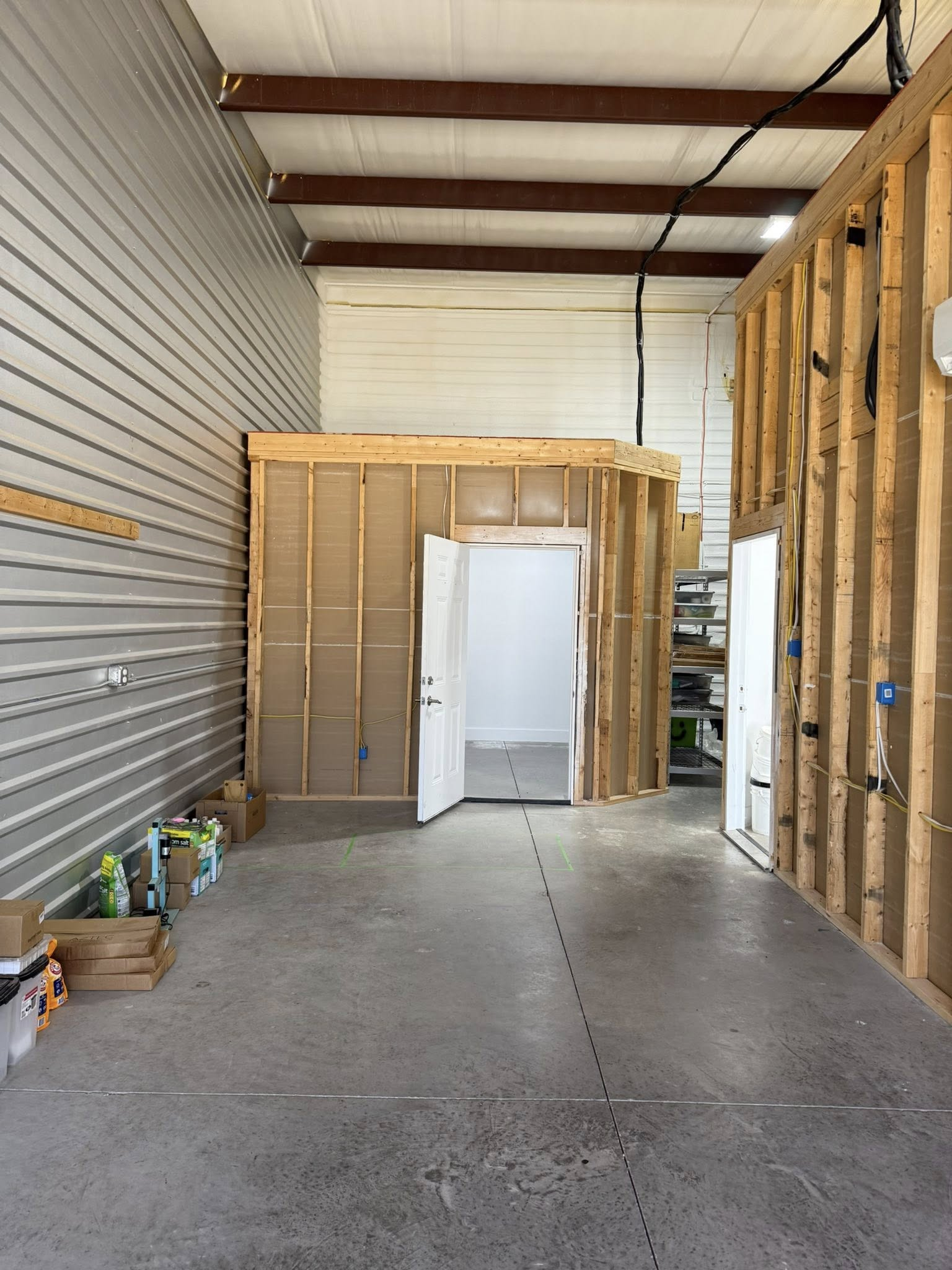 Interior of a building under construction, showing exposed studs, doorway, and unfinished walls.