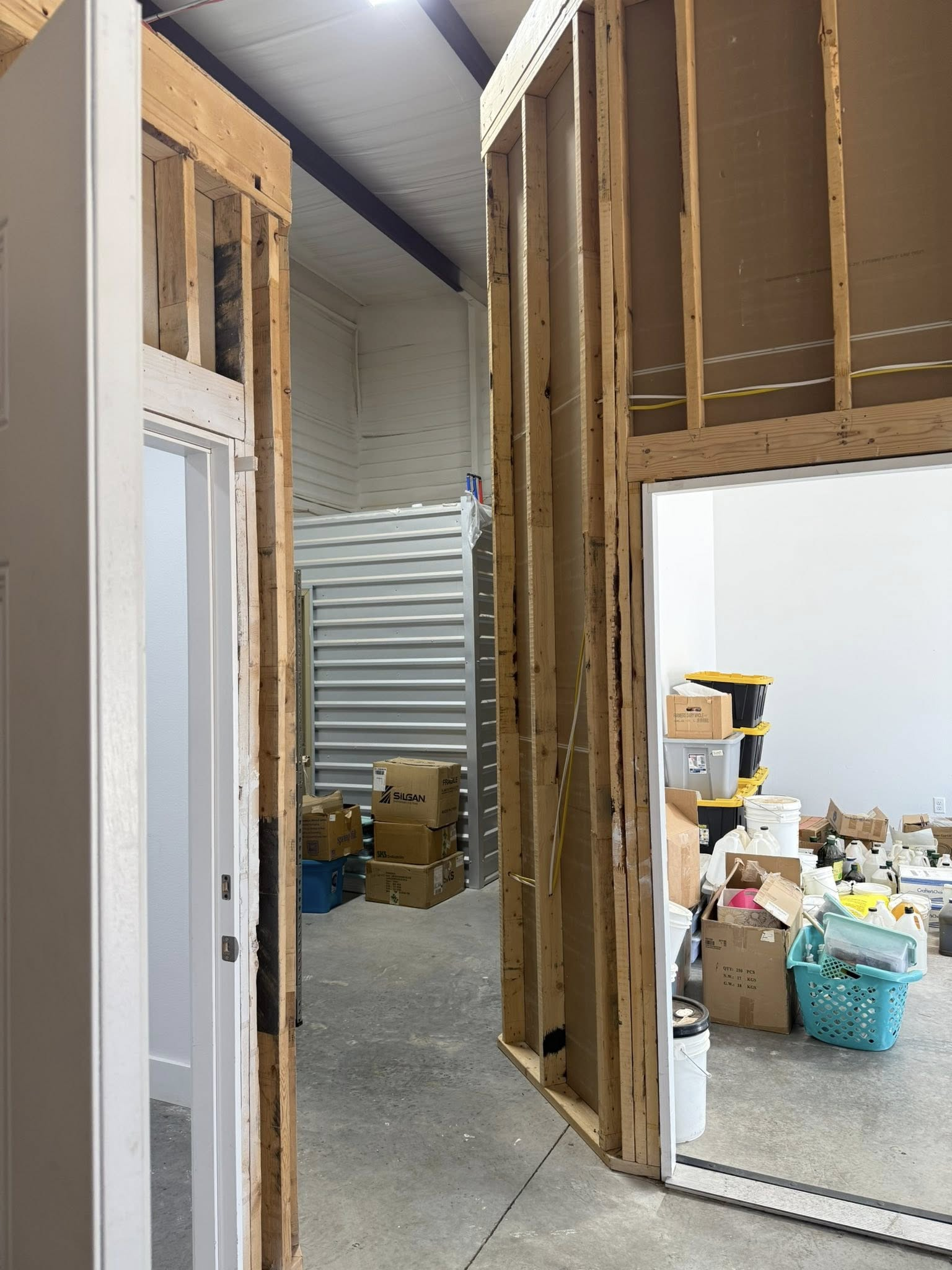 Framing of doorways in a building with a storage area, boxes, and various objects visible.