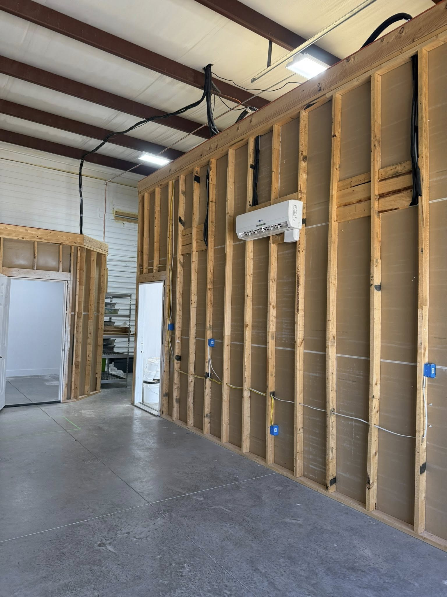 Interior construction of a room with exposed wooden studs and an air conditioning unit installed.