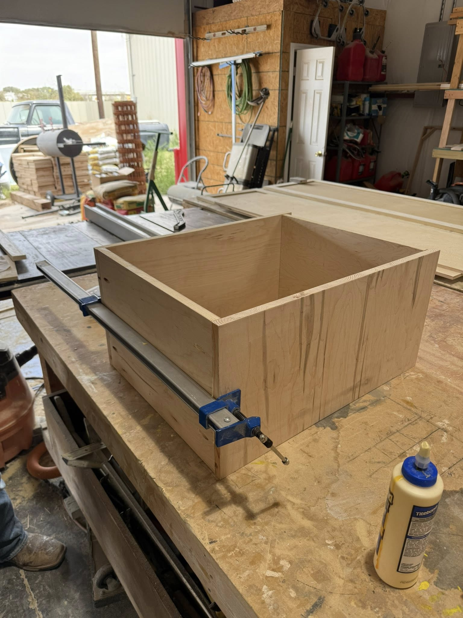 A wooden box being assembled with clamps on a workbench in a workshop.