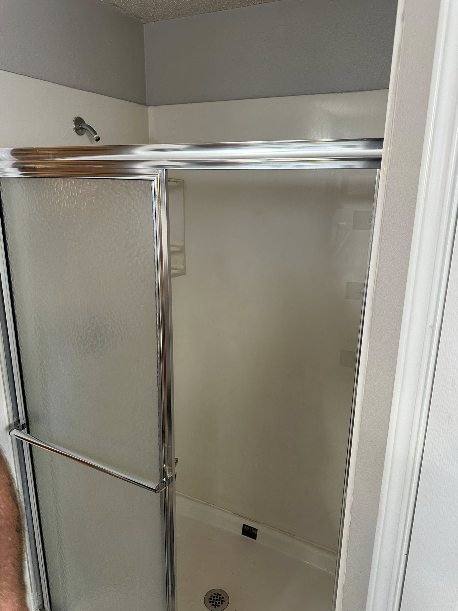 Shower stall with sliding glass doors and chrome trim. White walls.