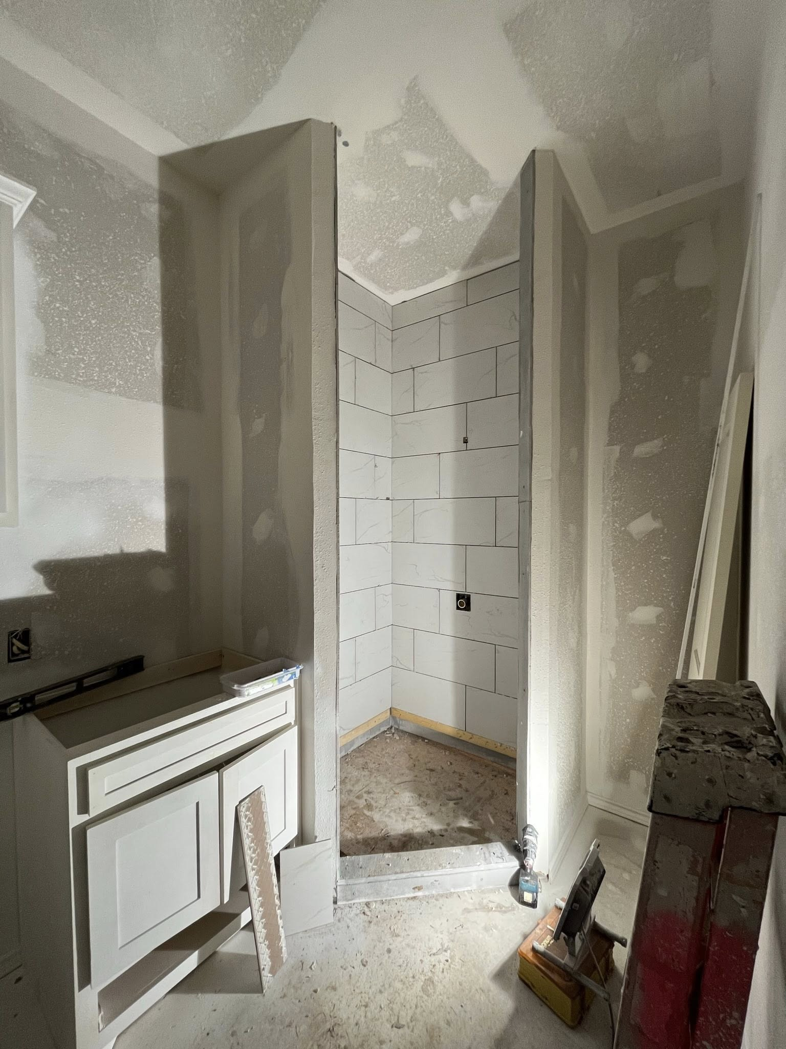 Bathroom under construction; drywall installed around a shower stall, vanity present.