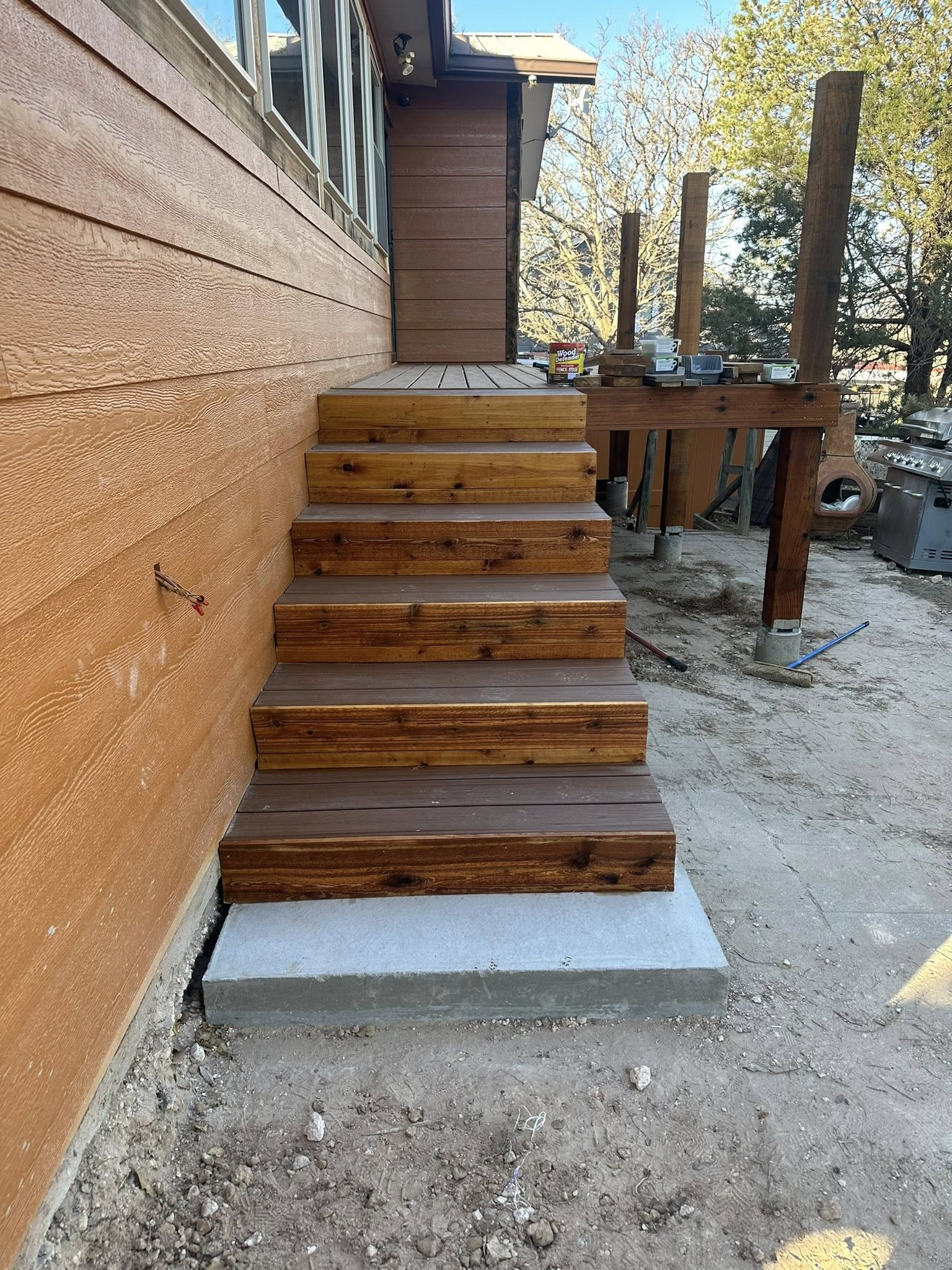 Wooden stairs leading up to a building's entrance. The stairs are brown, with a concrete base.