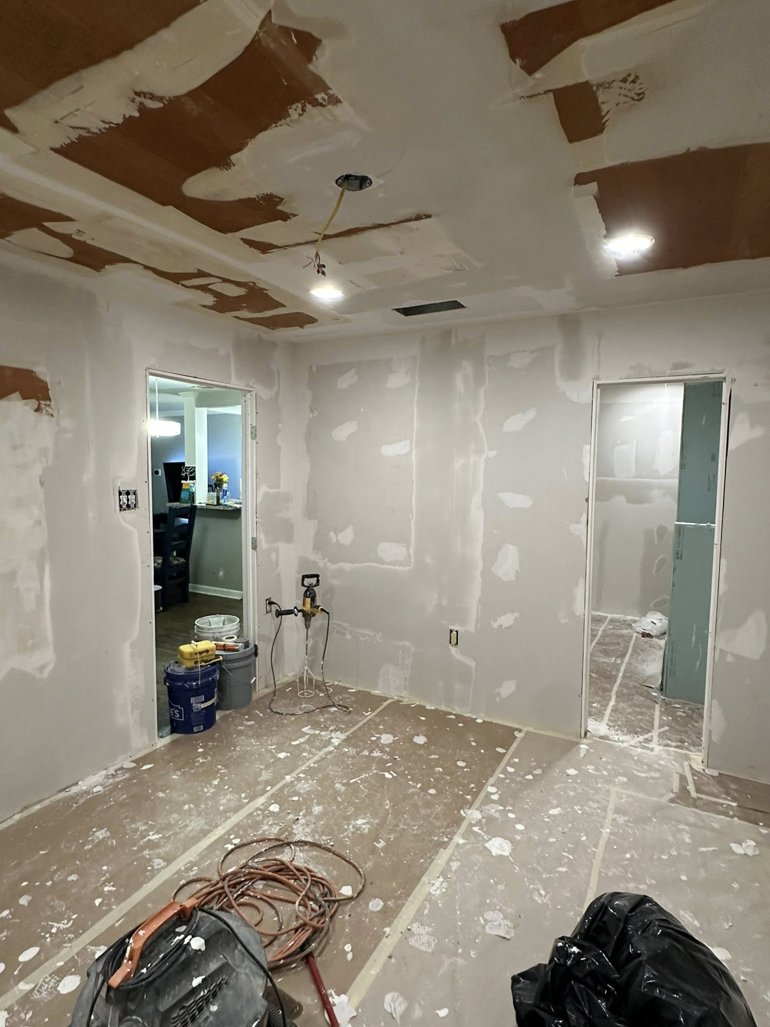 Room under construction, drywall installed, spackle on walls, tools on floor.