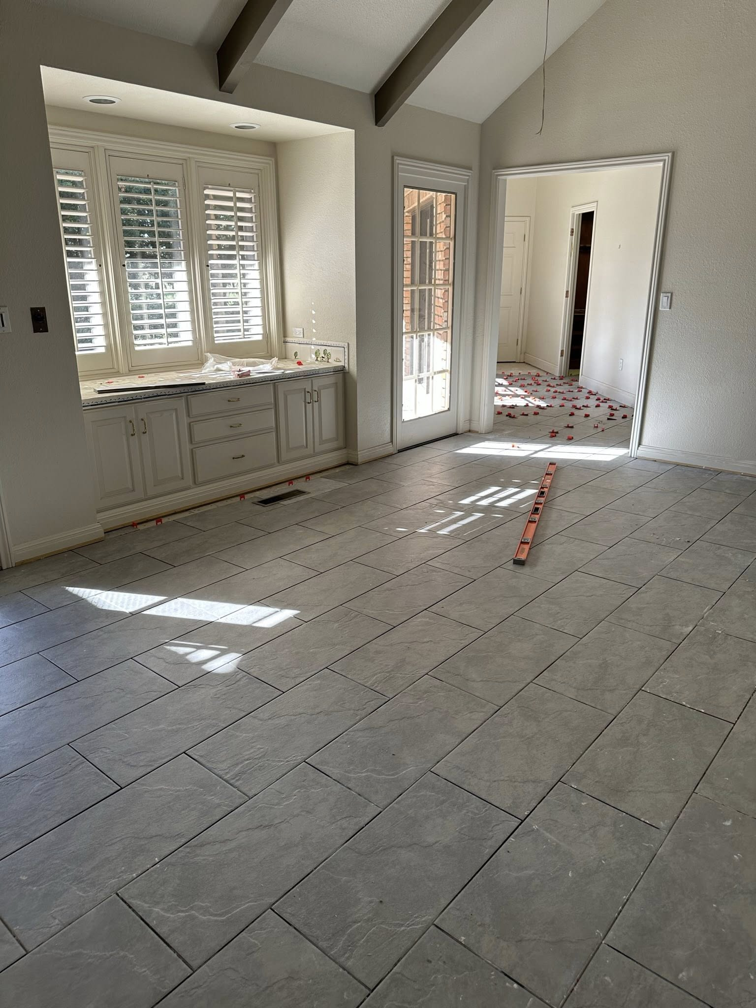 Interior room with newly installed gray floor tiles, bay window, and open doorway.