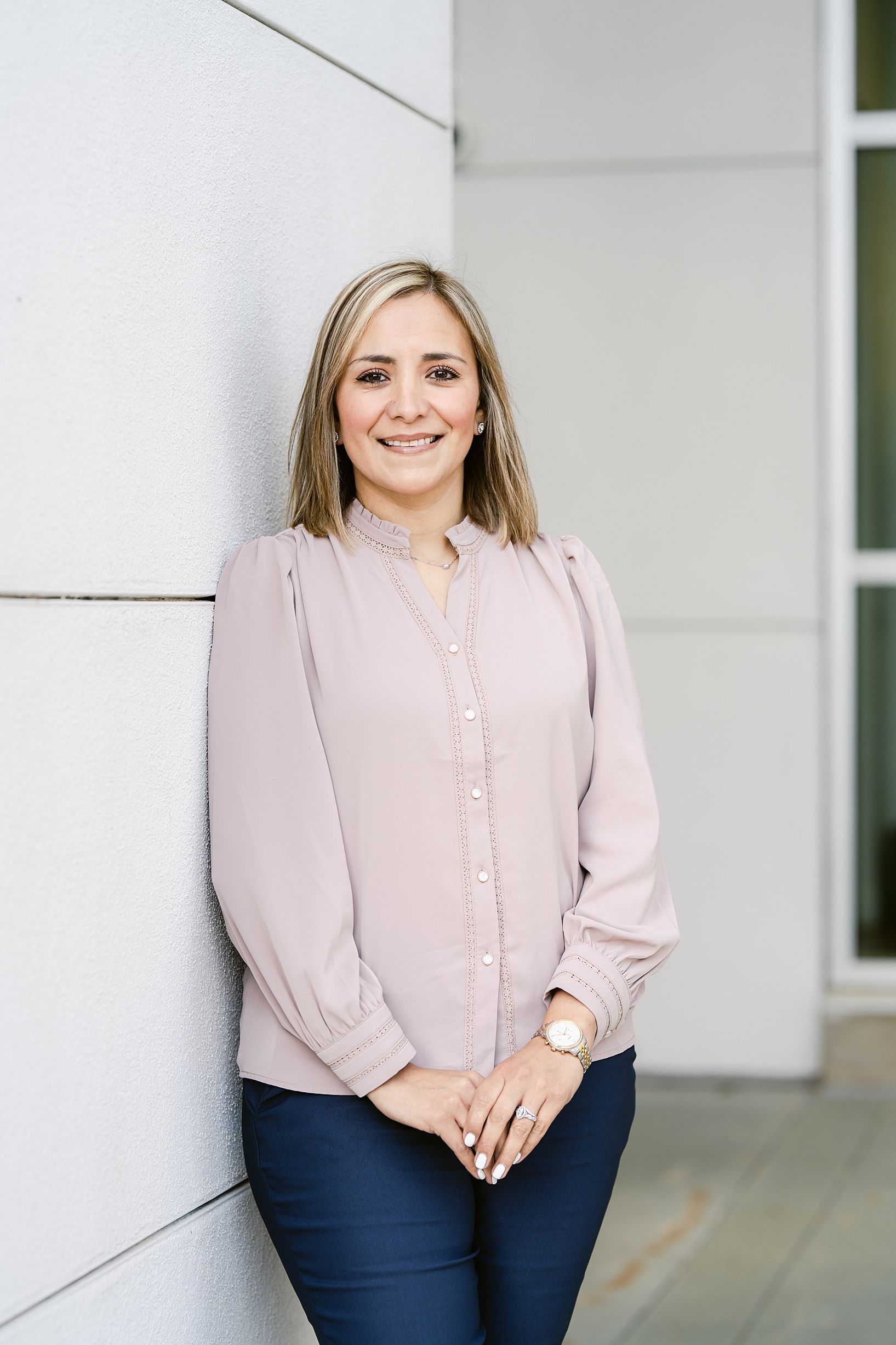 Jessika Mohr with brown hair in blue blouse smiling on a gray couch.
