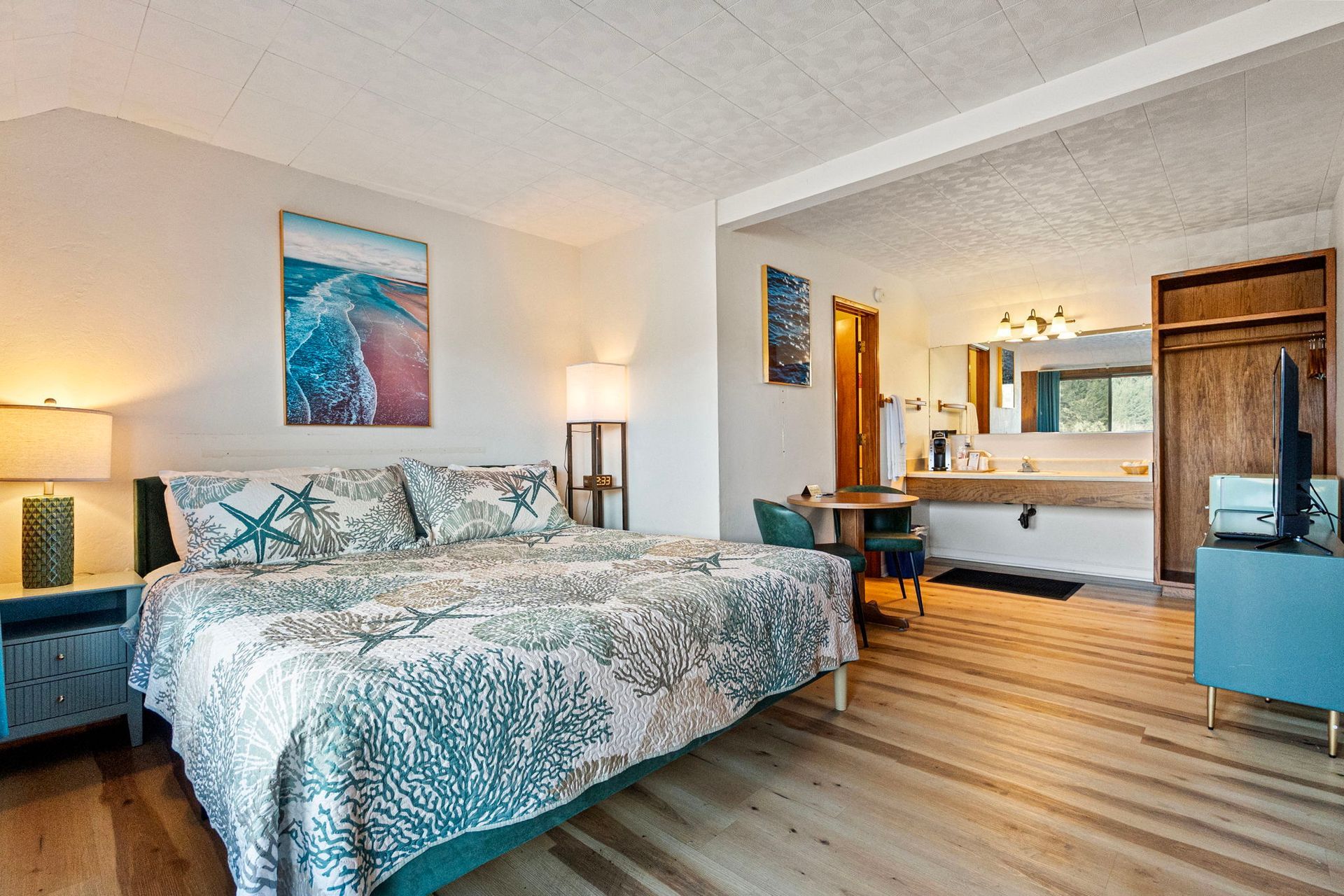 Bedroom with double bed, two nightstands with lamps, round table, open bathroom door.