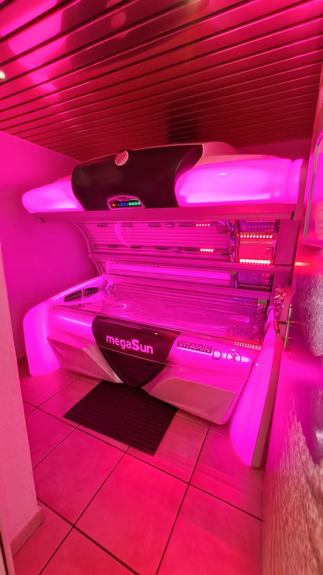 Eine megasun Sonnenbank 7900 alpha deluxe mit einem rosa Licht darauf 