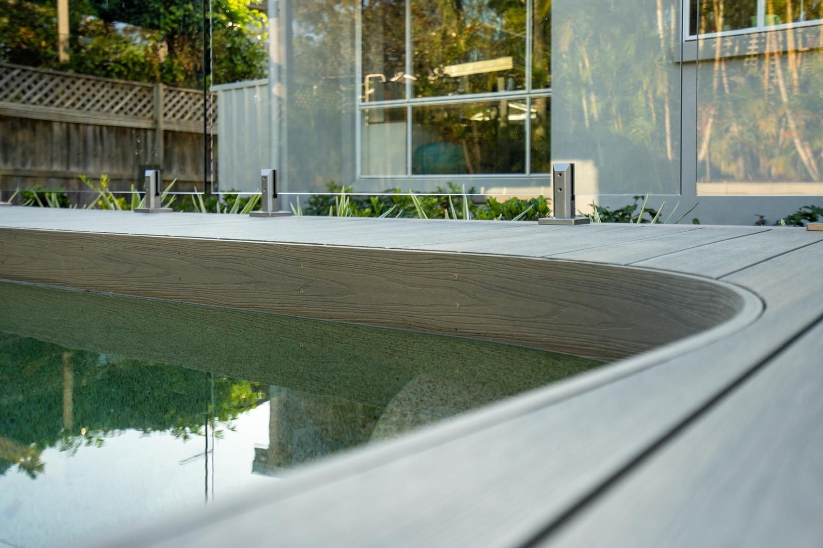 A swimming pool is surrounded by a deck and a house.