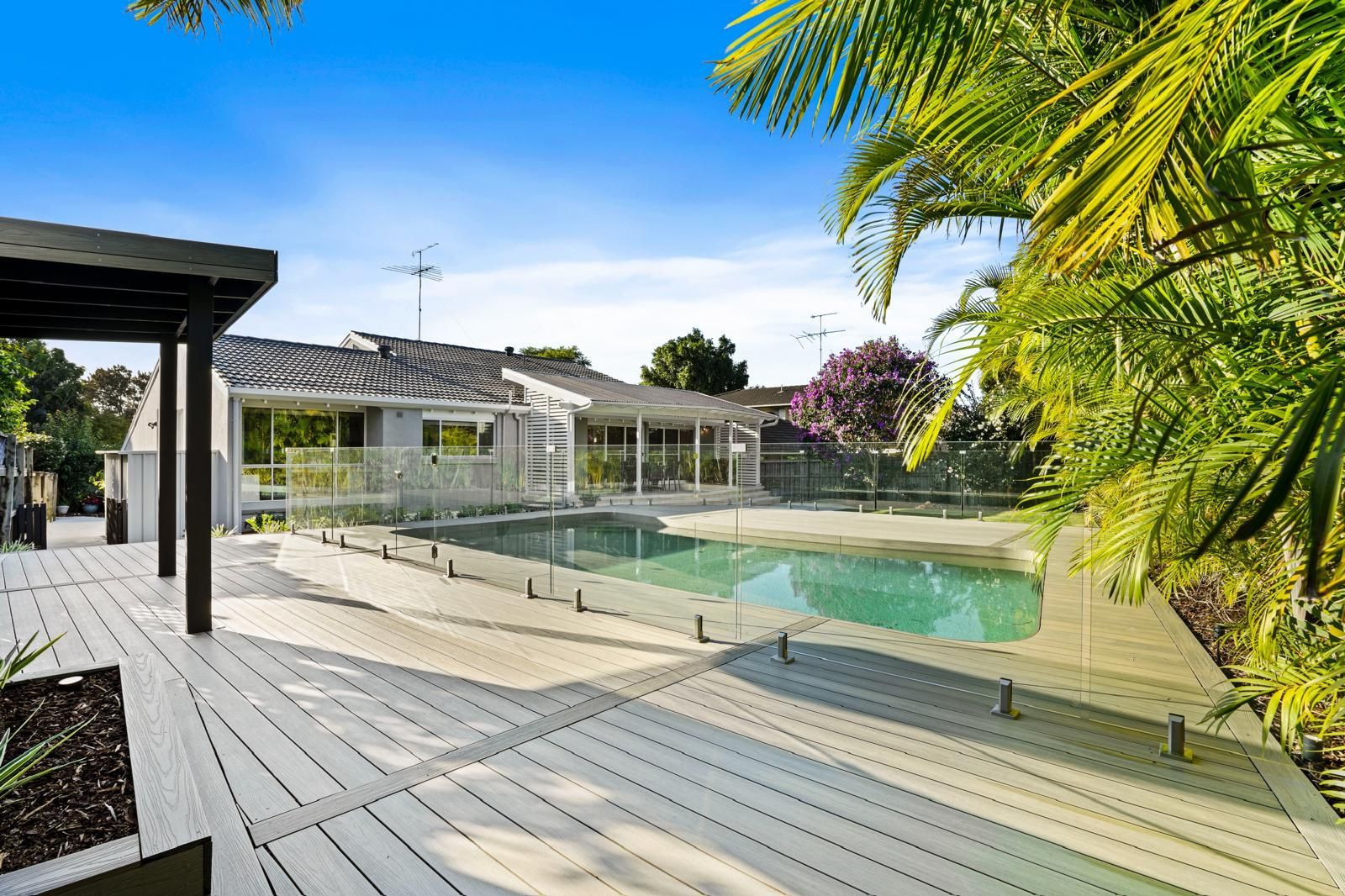 There is a large swimming pool in the backyard of a house.