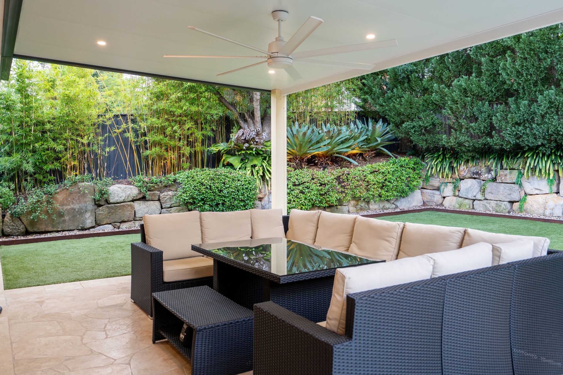 A patio with a couch , table , and ceiling fan.