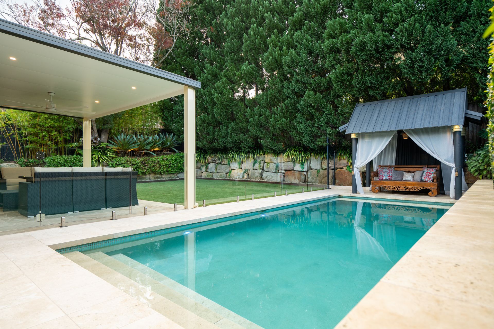 A large swimming pool with a gazebo and a hot tub in the backyard.