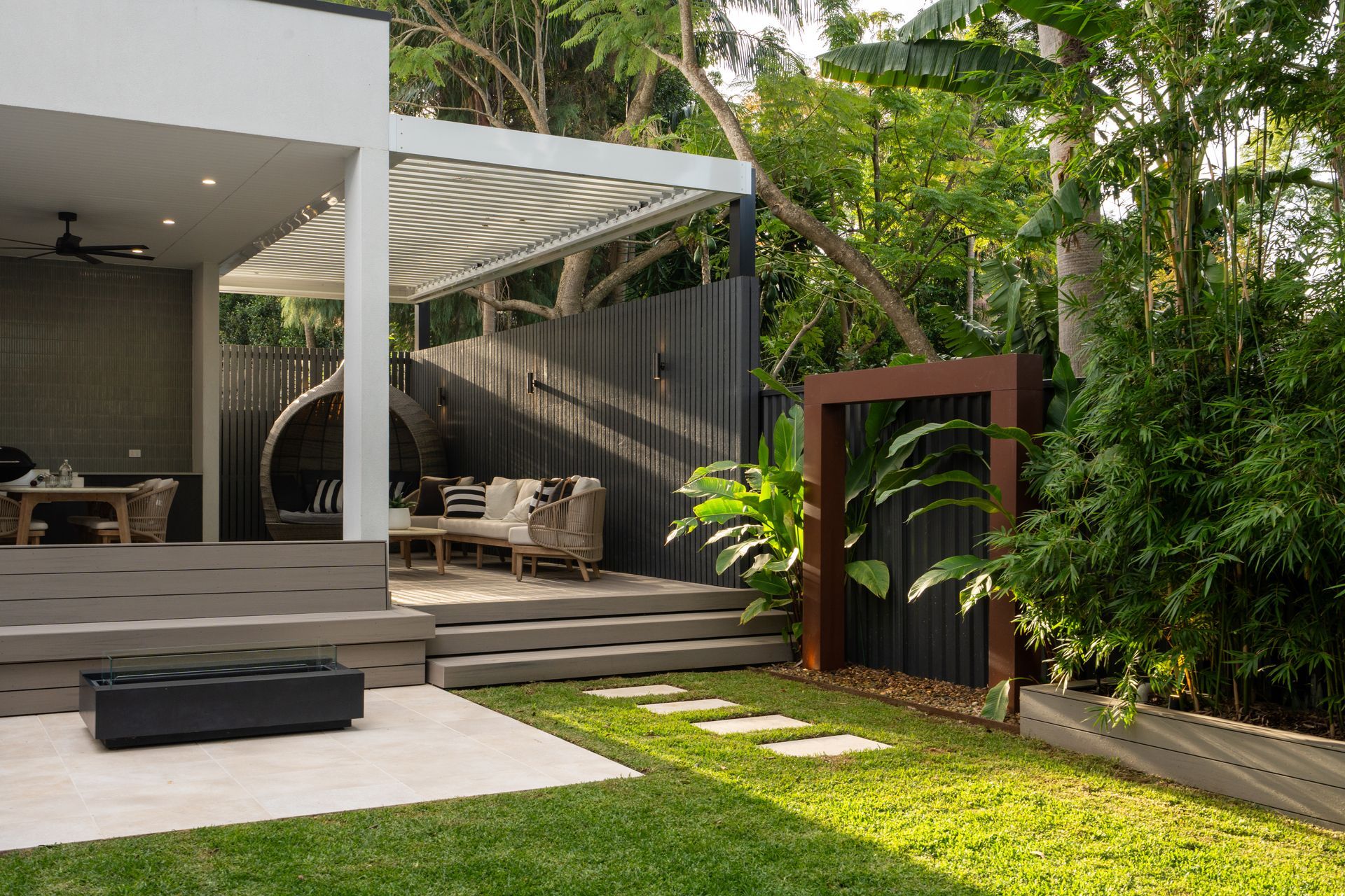A backyard with a patio and a fence surrounded by trees.