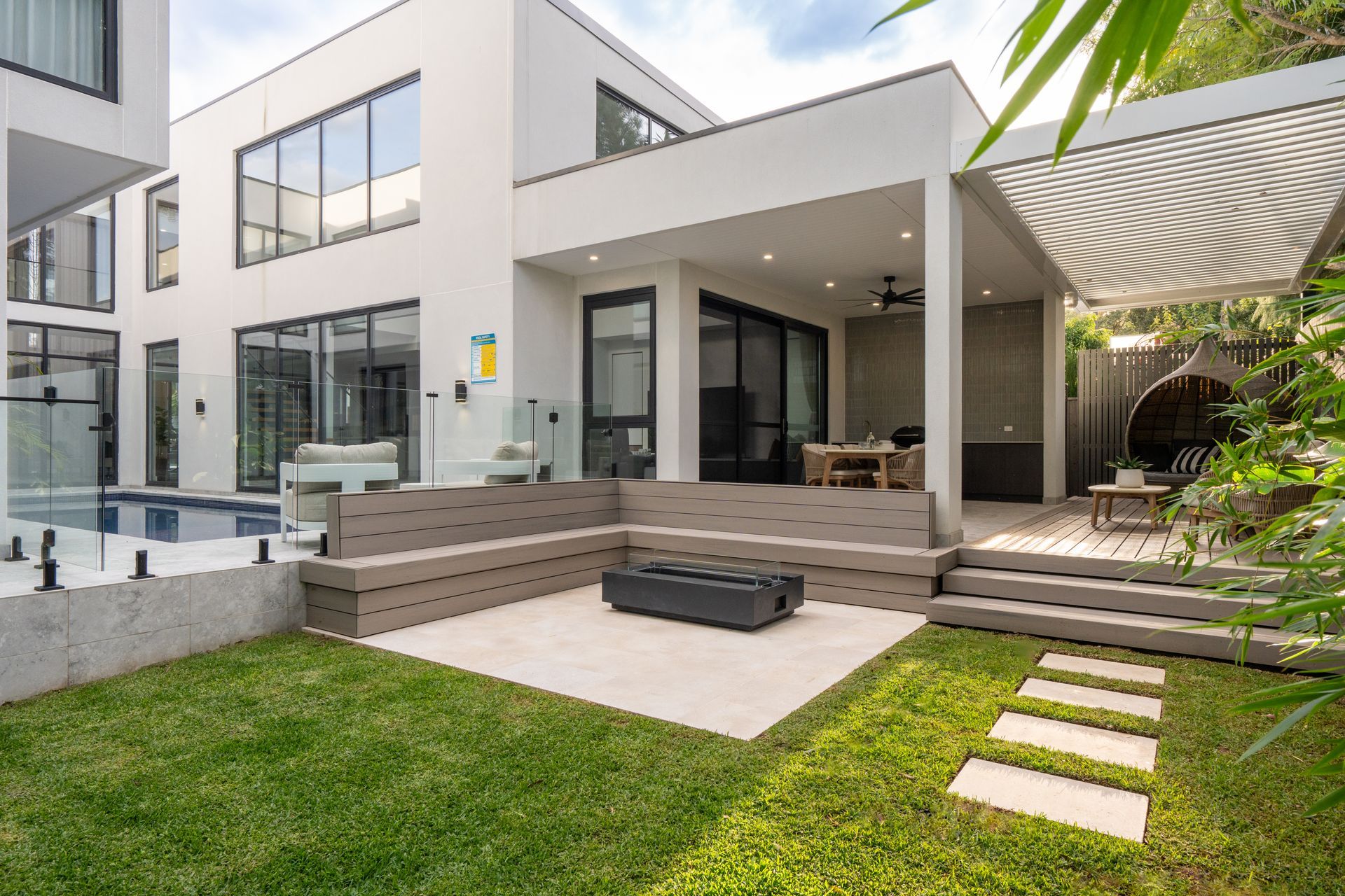 Modern white two-story house with backyard patio, grass, and a swimming pool.