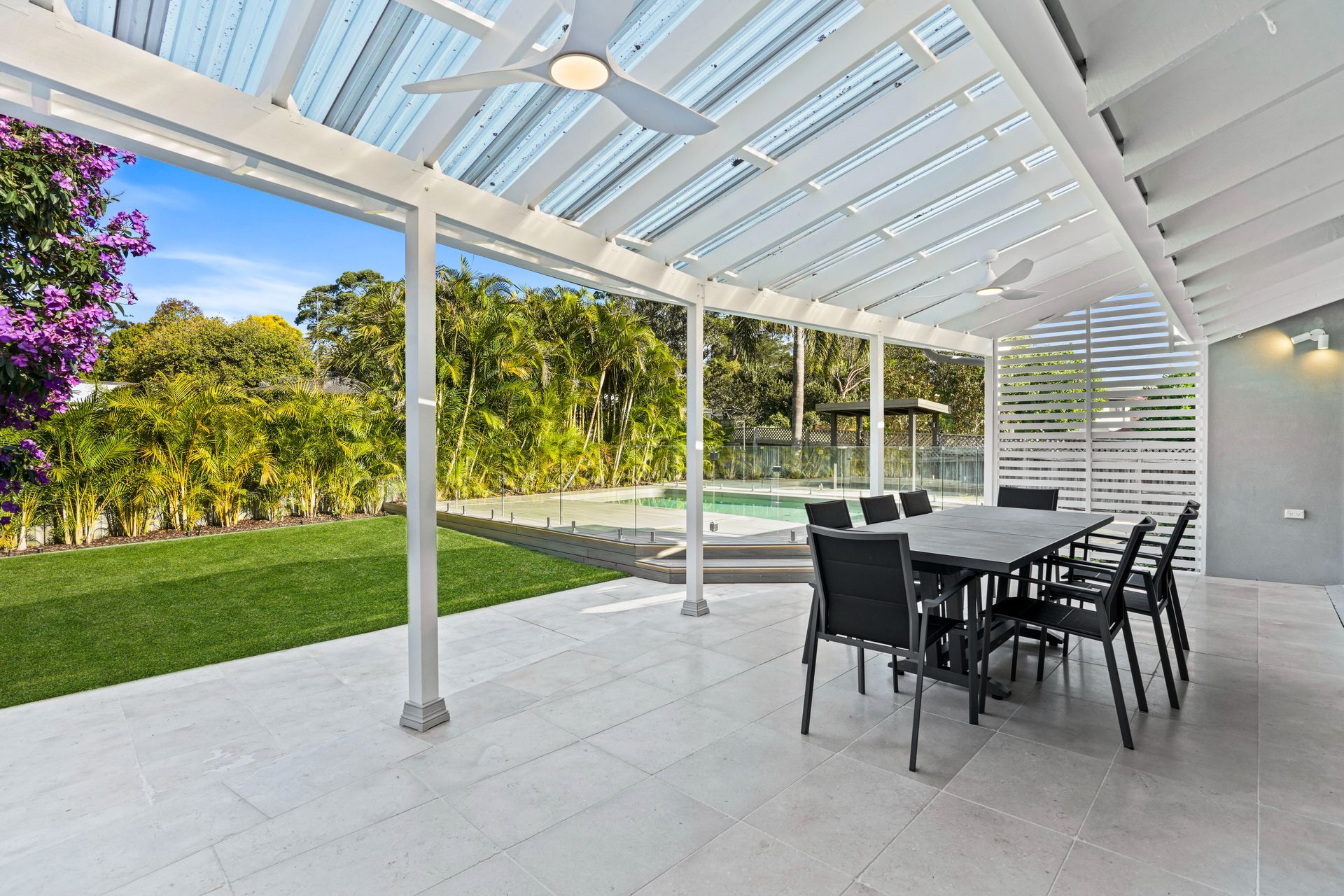 A patio with a table and chairs and a ceiling fan.