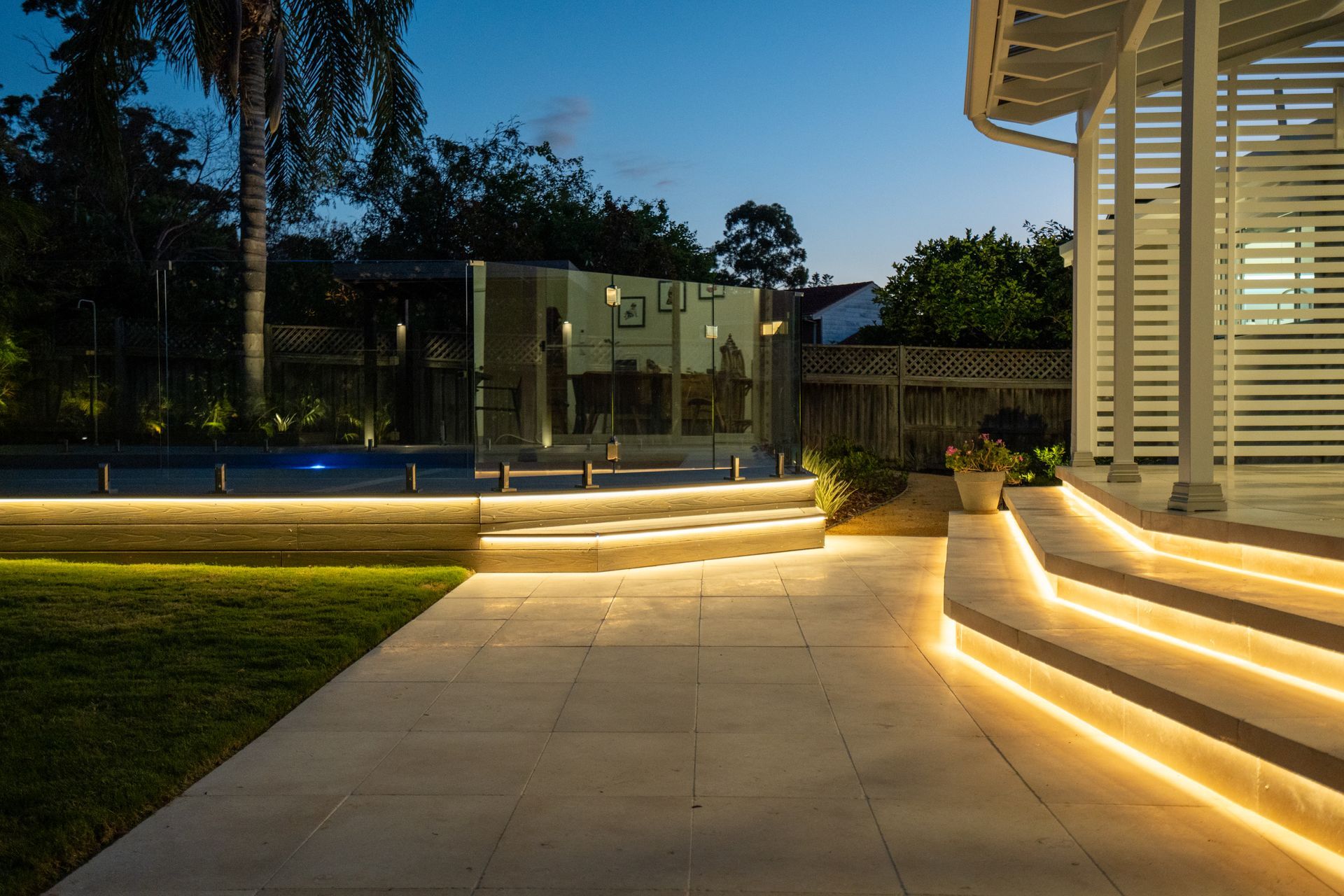 The stairs are lit up at night and there is a pool in the background.
