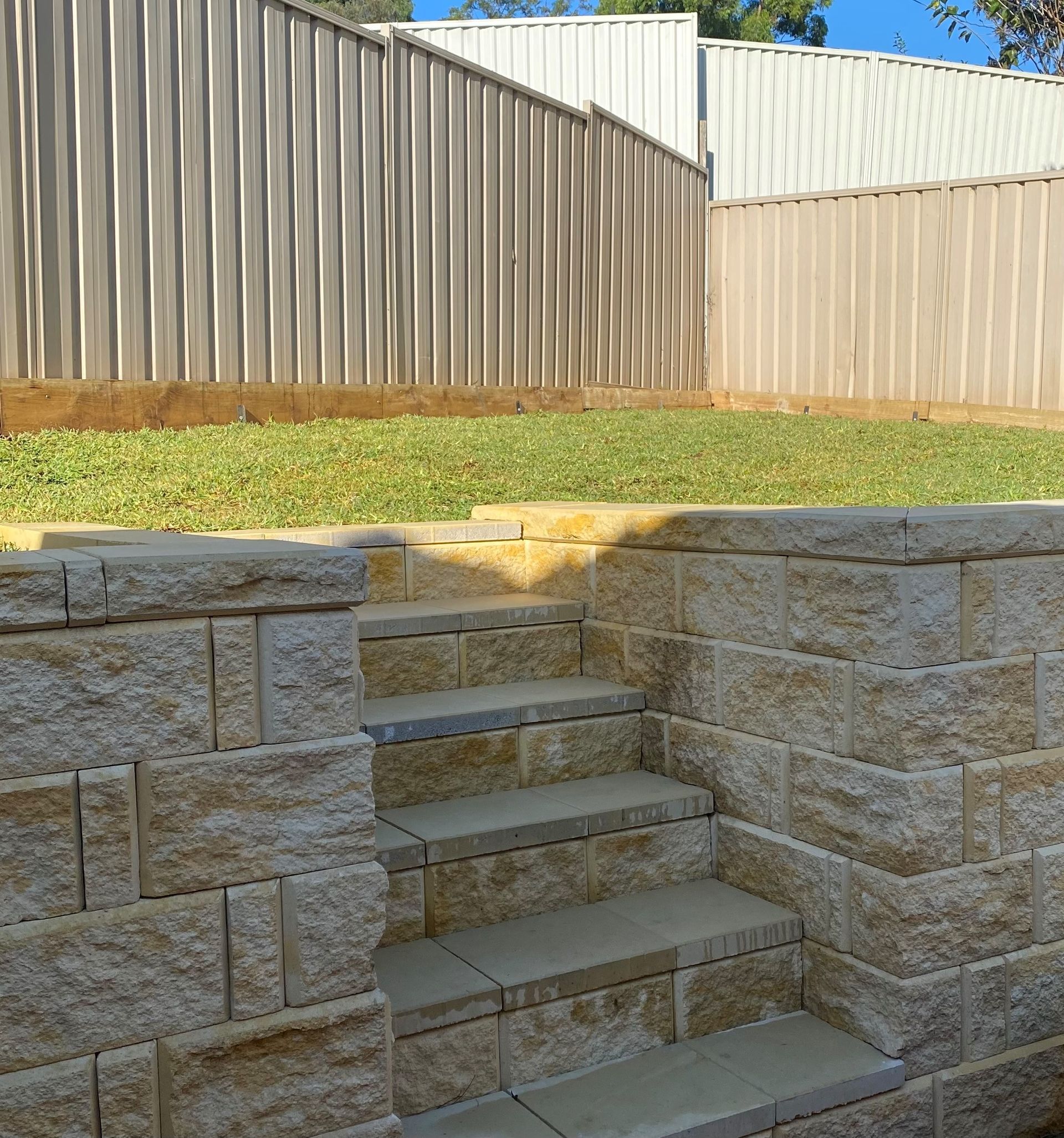 A stone wall with stairs leading up to a fence.