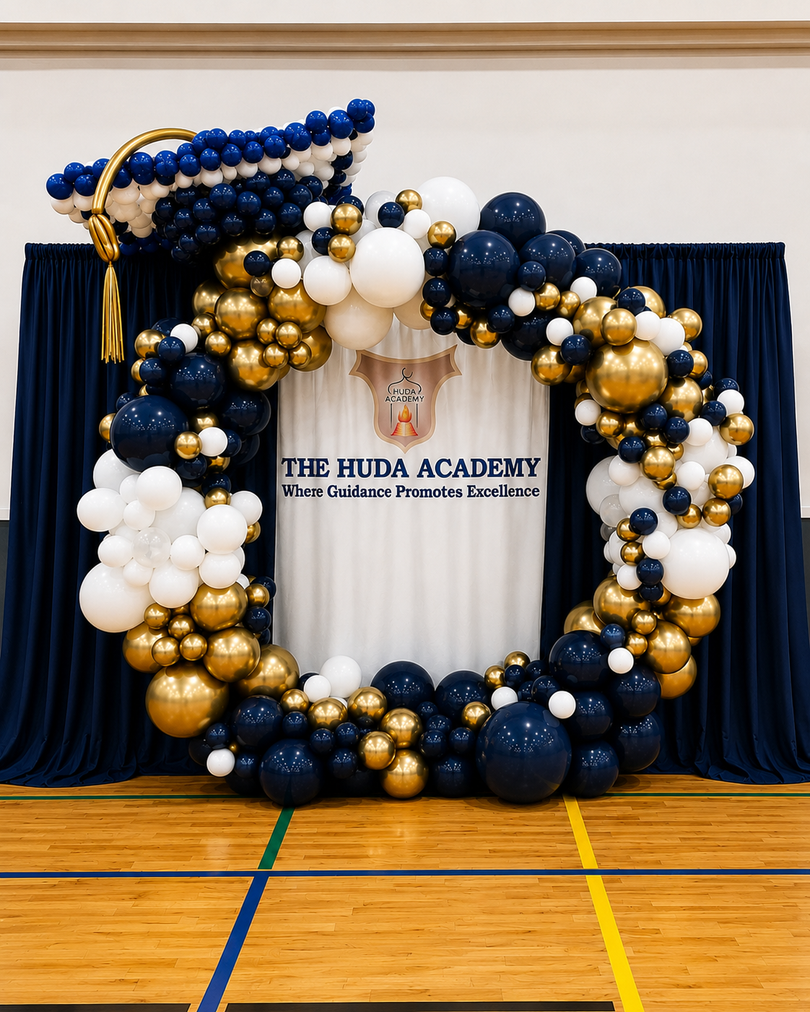 Balloon graduation display in navy, gold, and white in front of a school stage backdrop