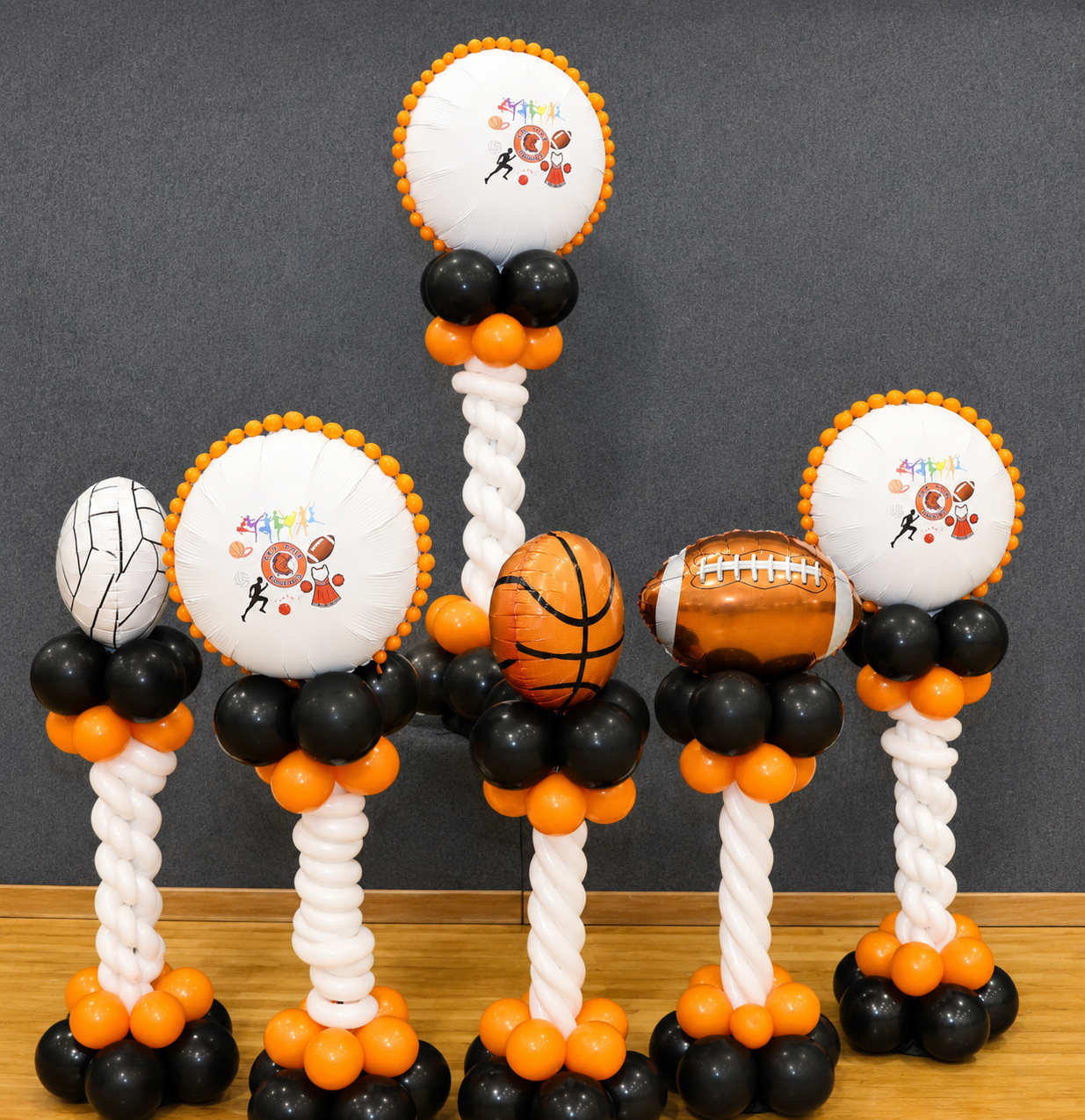 Halloween balloon centerpiece with black, orange, and white balloon columns and sports-ball toppers on a table