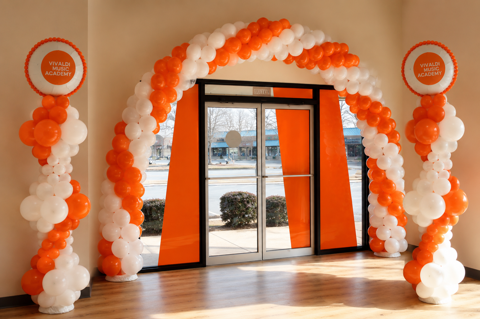 Orange and white balloon arch framing a doorway in a decorated event space