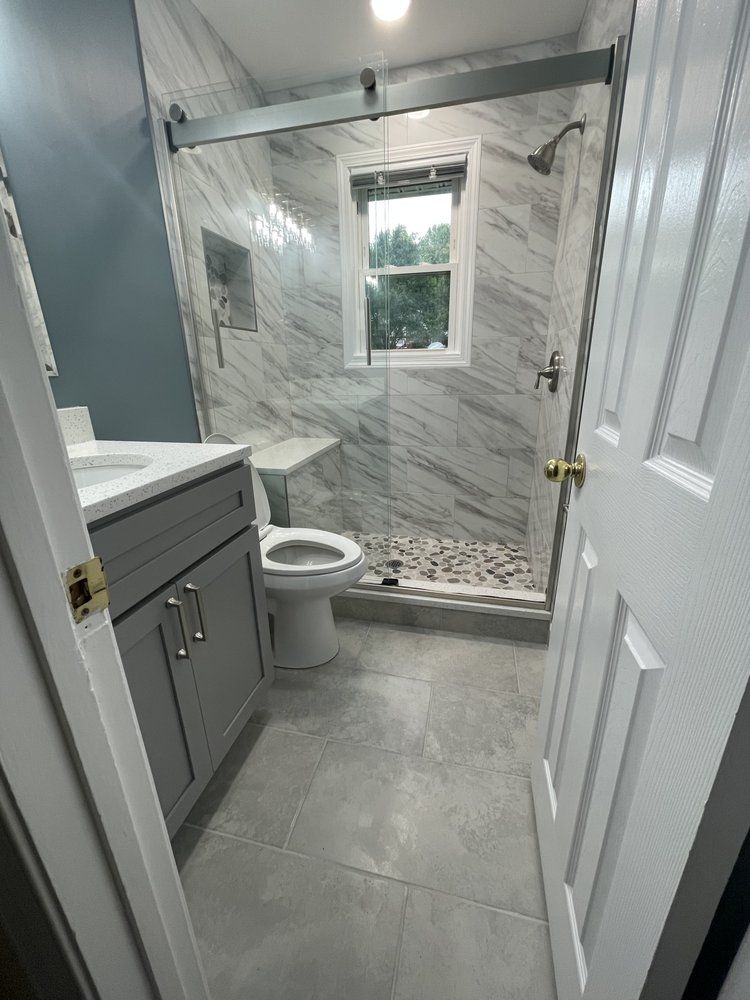 A bathroom with a toilet , sink , shower and window.