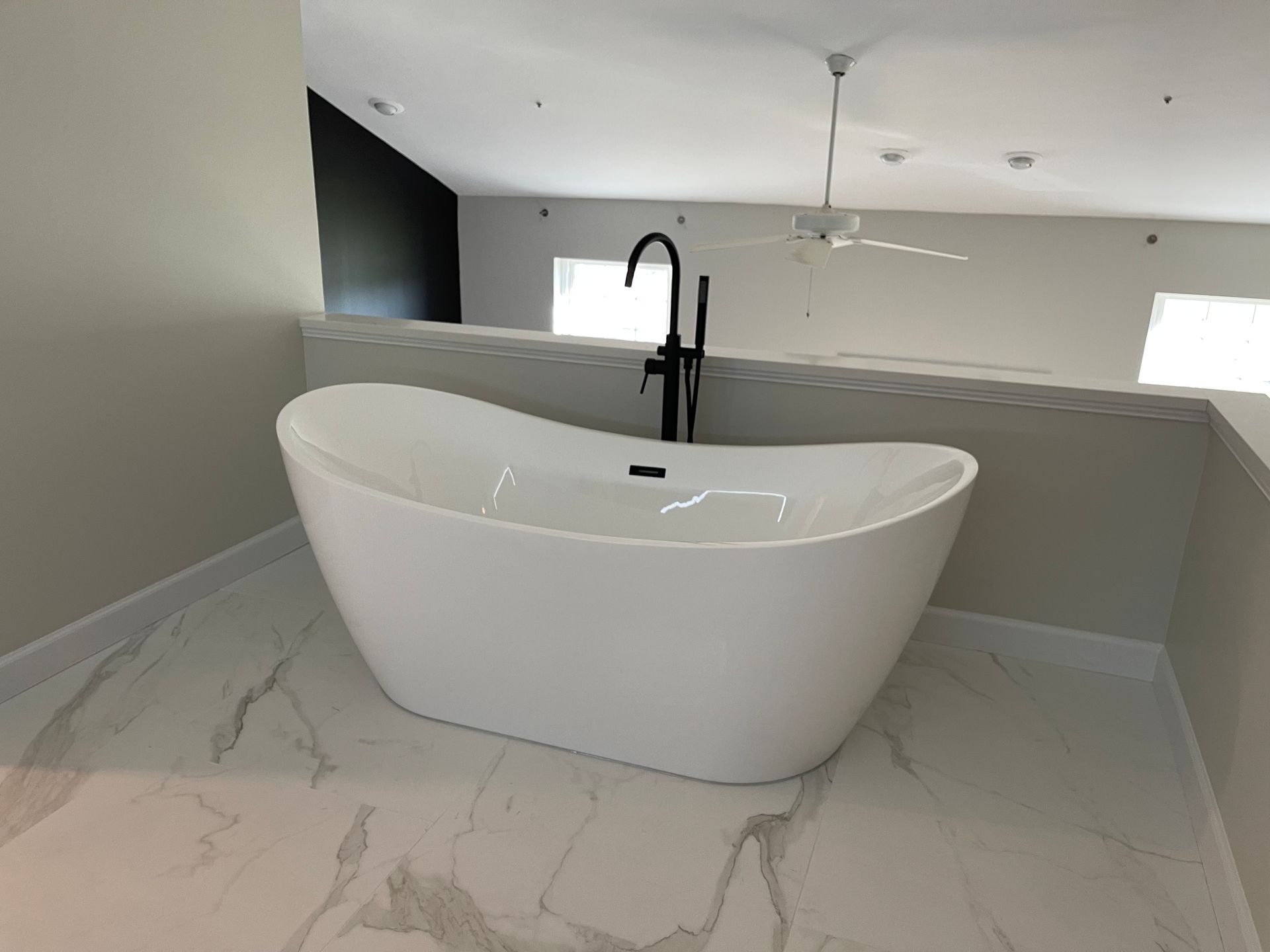 A white bathtub is sitting on a marble floor in a bathroom.